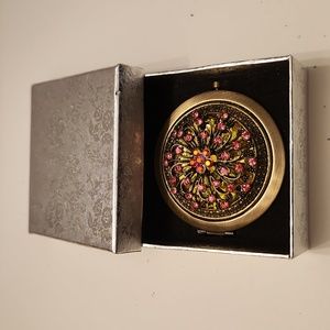 Double sided compact mirror, brass colored with pink stones.